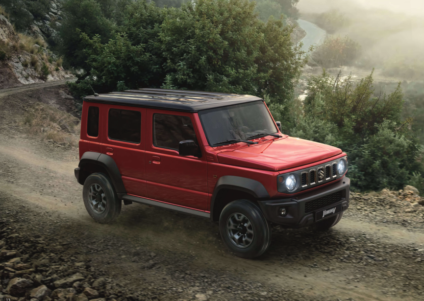 A red Suzuki Jimny 5-Door driving on a gravel road